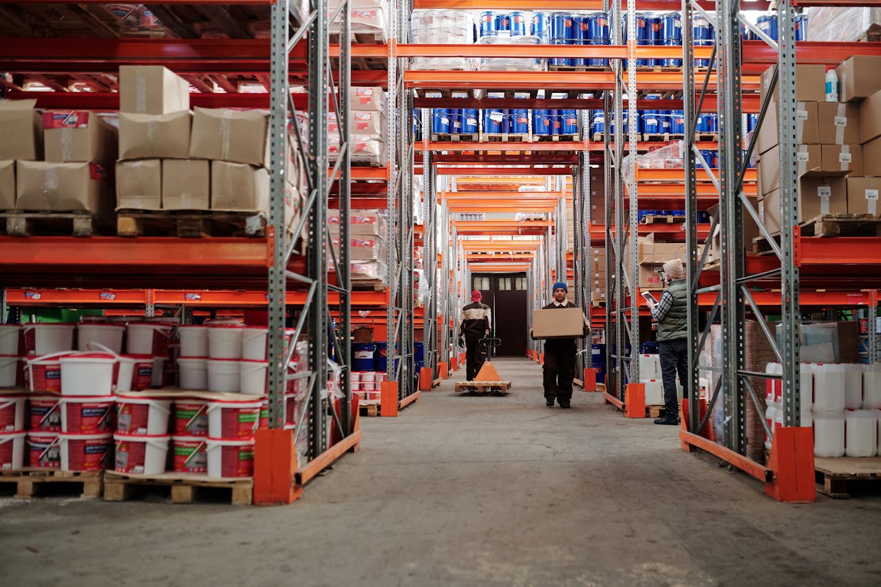 portfolio-01 Warehouse interior showing workers handling boxes and organized shelves filled with products.